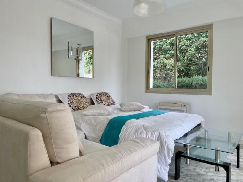 a white living room with a couch and a glass table at Rez de jardin de 65m2 dans villa à Nice in Nice