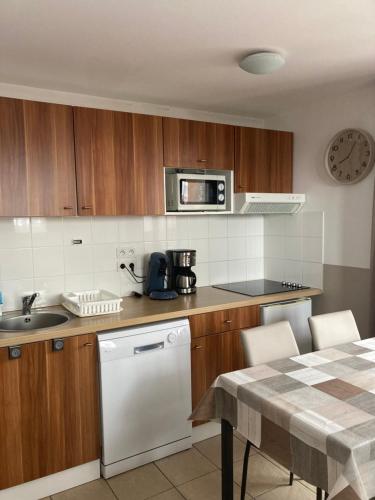 a kitchen with wooden cabinets and a white dishwasher at 2 pièces, au pied des pistes ds Résidence Gd Hôtel in Valberg