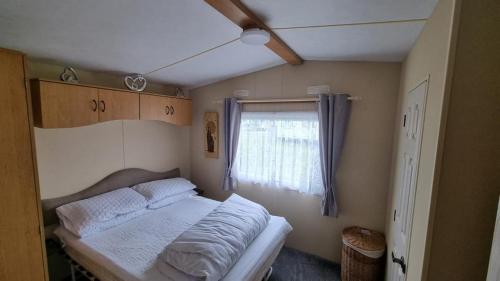 a small bedroom with a bed and a window at E16 Millfields 6 berth caravan MAX 4 ADULTS Bob family's only and lead person must be over 30 in Ingoldmells