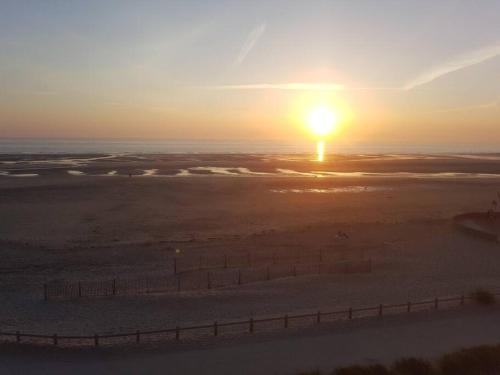 un tramonto sull'oceano con una recinzione in primo piano di FORT MAHON superbe appartement face mer a Fort-Mahon-Plage