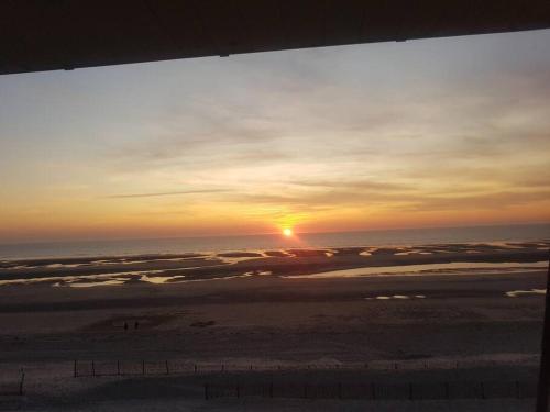 un tramonto sull'oceano con il sole nel cielo di FORT MAHON superbe appartement face mer a Fort-Mahon-Plage