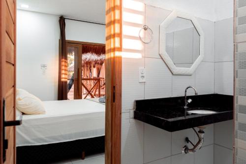 uma casa de banho com um lavatório, uma cama e um espelho. em Pousada Vila Tapera em Barra Grande