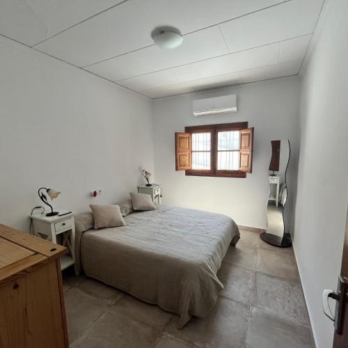 a white bedroom with a bed and a window at Villa Rios in Xàtiva