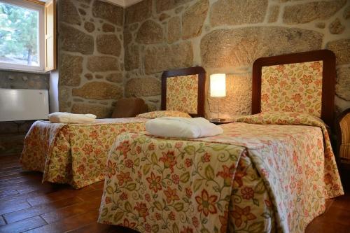 1 dormitorio con 2 camas y pared de piedra en Casa Lagar da Moira, en Vila Franca da Serra