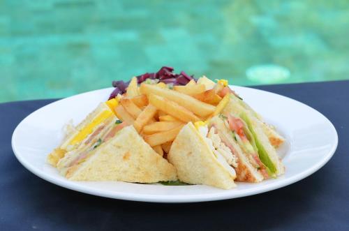 eine weiße Platte mit einem Sandwich und Pommes frites in der Unterkunft Gili Air Lagoon Resort By Waringin Hospitality in Gili Air