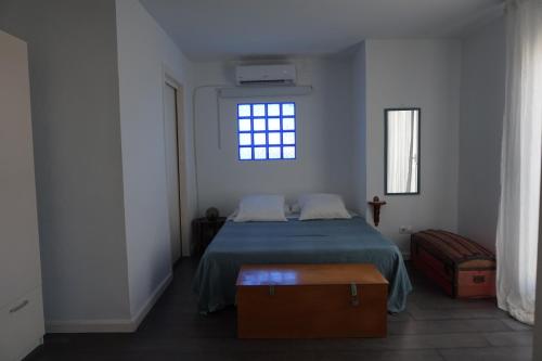 een slaapkamer met een bed met een blauwe deken en een raam bij IMPLUVIUM Conil-Terraza Privada-Parking- mayores de 25 años in Conil de la Frontera