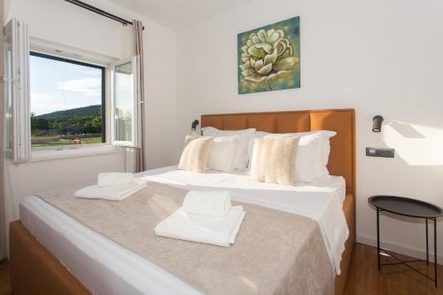 a bedroom with a large bed with white sheets and a window at Luxury Villa Lunika near Brela, Baska Voda, Makarska in Lovreć