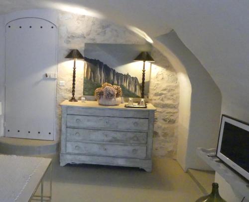 um quarto com uma cómoda com duas lâmpadas e uma televisão em Les Vieux Murs em Montfort
