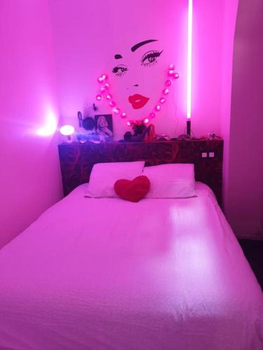 ein rosafarbenes Schlafzimmer mit einem Bett mit einer Frau mit Herzen in der Unterkunft Dieppe Love-amour in Dieppe