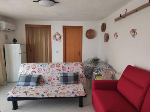 uma sala de estar com um sofá e uma cadeira vermelha em BILOCALE MAZZARELLI em Marina di Ragusa