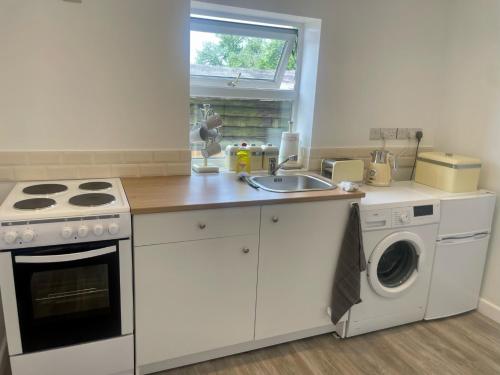 a kitchen with a sink and a washing machine at Shepherds Gate at The Royal Oak Much Marcle in Preston
