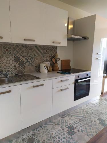 une cuisine avec des armoires blanches et un four à plaques de cuisson dans l'établissement Studio jardin et plage à 13 min à pied, à Fréjus