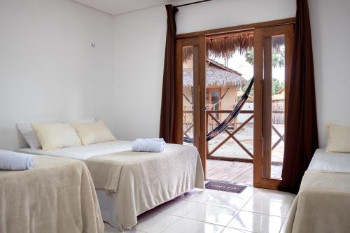 a room with two beds and a sliding glass door at Pousada Vila Tapera in Barra Grande