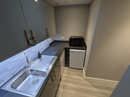 eine kleine Küche mit einer Spüle und einer Mikrowelle in der Unterkunft Wassells House Accommodation in Cheddar
