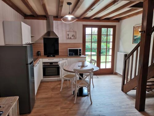a kitchen with a table and chairs and a kitchen with a refrigerator at Le manège Gite Etretat in Sainte-Marie-au-Bosc