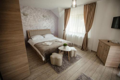 a bedroom with a bed and a table and a window at Pensiunea Alexandra 