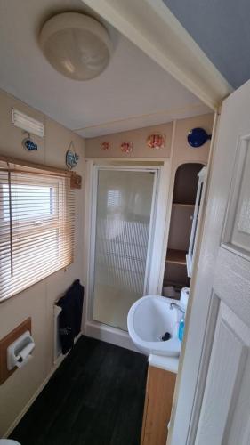 a small bathroom with a sink and a tub at E16 Millfields 6 berth caravan MAX 4 ADULTS Bob family's only and lead person must be over 30 in Ingoldmells