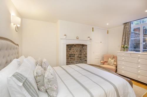 a white bedroom with a bed and a fireplace at The Garden Square - Unique luxury apartment in historic garden square - ideal for 2 people in York