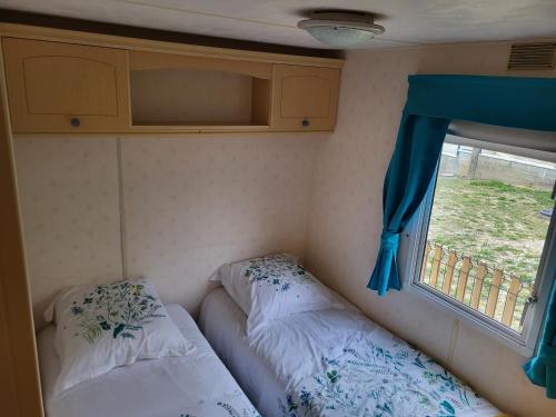 une petite chambre avec deux lits et une fenêtre dans l'établissement Mobil Home à la ferme, à Le Neufbourg