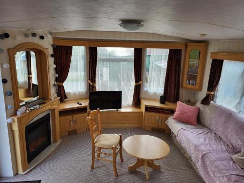 a living room with a couch and a table at Mobil Home à la ferme in Le Neufbourg