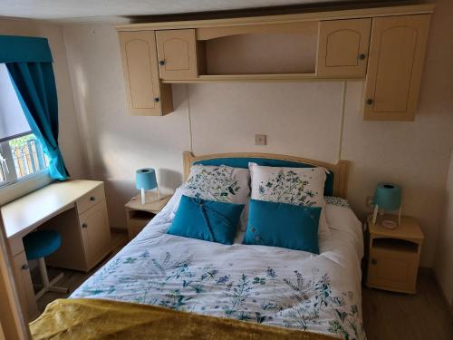 a small bedroom with a bed with blue pillows at Mobil Home à la ferme in Le Neufbourg