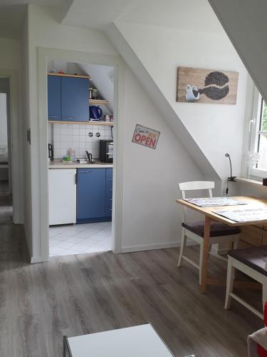 a kitchen and dining room with blue cabinets and a table at FeWo Baron in Kleinwessek