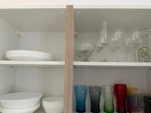 ein Regal mit Gläsern, Platten und Schalen in der Unterkunft 2 Ferienwohnungen in einem Haus mit EBK, WLAN, SELF-CHECK-IN in Ittlingen