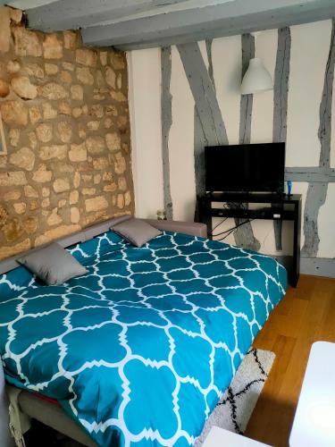 une chambre avec un lit bleu et une télévision dans l'établissement Studio charme Haut-Marais, à Paris