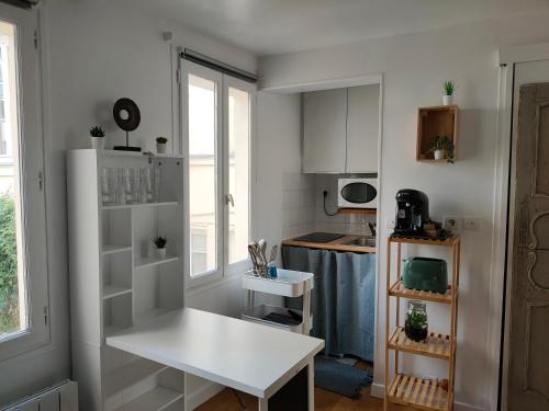Il comprend une cuisine équipée d'une table blanche et d'un réfrigérateur blanc. dans l'établissement Studio charme Haut-Marais, à Paris