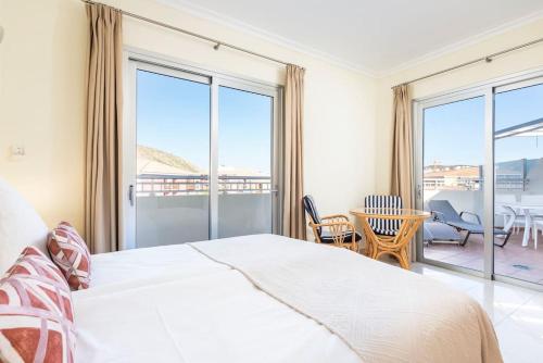 a bedroom with a white bed and a balcony at Luxuriöse Duplex Ferienwohnung in sehr ruhiger Wohnanlage mit Meerblick in Palm-mar