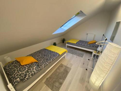 1 dormitorio en el ático con 2 camas y ventana en Ferienwohnung Eifel Stadtkyll, en Stadtkyll