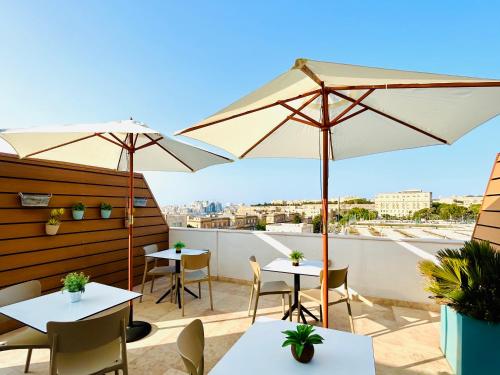 a patio with tables and umbrellas on a roof at Tritoni Valletta Boutique Hotel in Il-Furjana