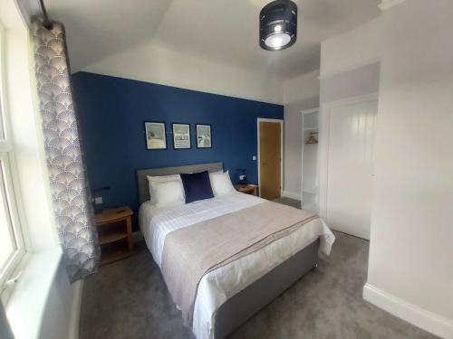 a bedroom with a large bed with a blue wall at Bay House in Totland