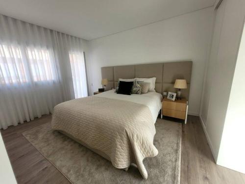 a white bedroom with a large bed and two lamps at Cidade_Berço House in Guimarães
