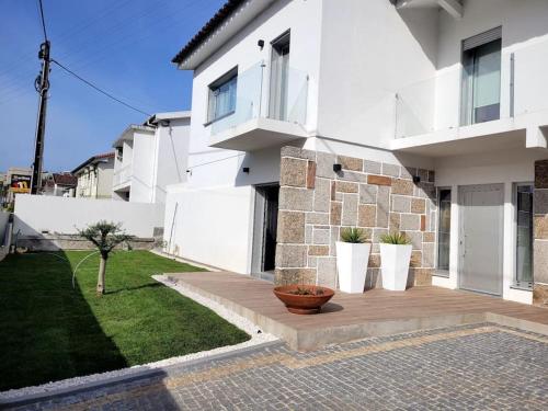 una casa bianca con vasi di piante su un patio di Cidade_Berço House a Guimarães
