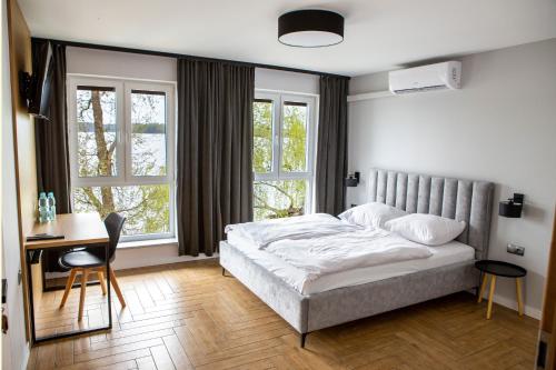 1 dormitorio con 1 cama, escritorio y 2 ventanas en Przystań Posmakuj en Tereszewo