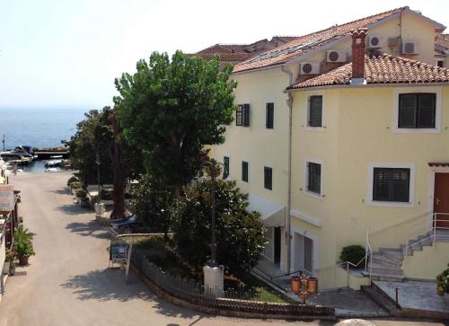 a large white building with trees and a street at Placa Apartments in Mošćenička Draga