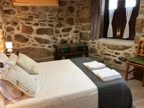 Cama en habitación con pared de piedra en Casa dos Senadores by Vale do Zêzere Hotel en Manteigas