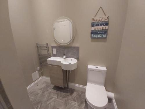 a bathroom with a toilet and a sink and a mirror at Bay House in Totland