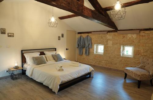 a large bedroom with a large bed and a chair at Gite Rural La Maison Mauve in Ventouse