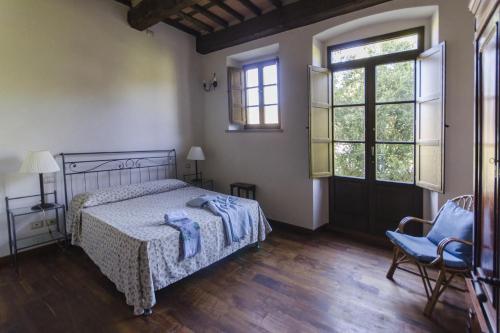 a bedroom with a bed and a chair and windows at Villa Sardini in Lucca