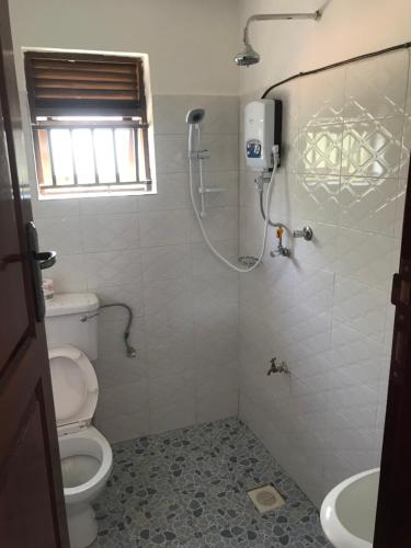 een badkamer met een douche, een toilet en een wastafel bij BIMS Vacation Rental in Fort Portal