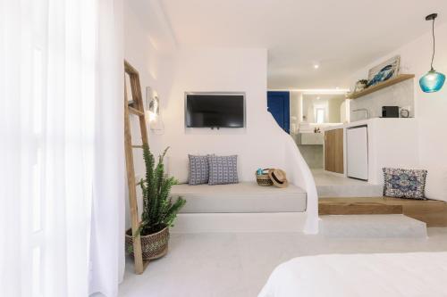 a white living room with a couch and a tv at Athina Studios and Suites Plaka in Plaka