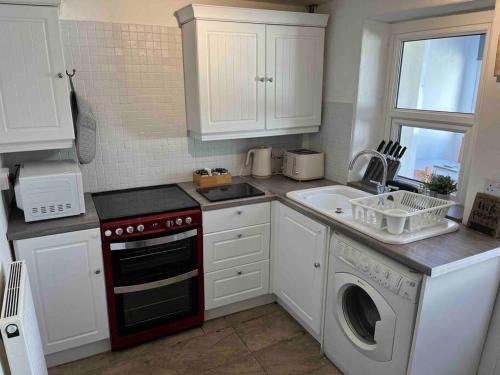 a kitchen with a sink and a stove and a dishwasher at Fisherman Cottage Morecambe in Morecambe
