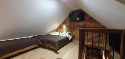Pokój na poddaszu z 2 łóżkami i ceglaną ścianą w obiekcie Domki letniskowe "U Adaska" w Chałupach