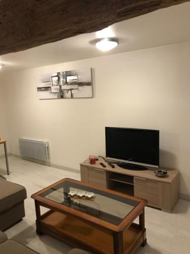 ein Wohnzimmer mit einem TV und einem Couchtisch in der Unterkunft Maison chaleureuse au centre ville in Nérac