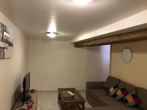 a living room with a couch and a tv at Maison chaleureuse au centre ville in Nérac