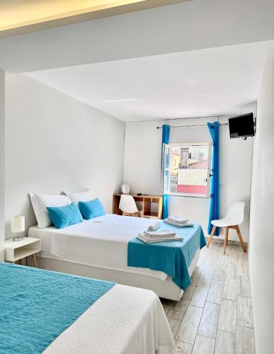 a white bedroom with two beds and a window at Enjoy Viana - Guest House in Viana do Castelo