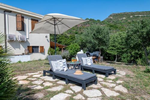 a patio with two chairs and a table with an umbrella at SARDINIA RE - Casa Luisa With Pool in Alghero