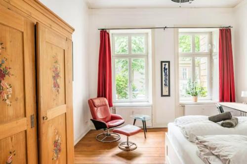 um quarto com uma cama e uma cadeira vermelha em Großzügige Altbauwohnung in Bestlage em Hamburgo